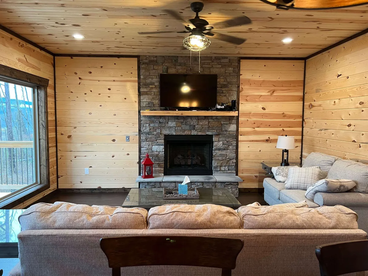 A cozy living area featuring a roaring fireplace, comfortable seating, and a large window that lets in natural light and offers an unobstructed view of the surrounding mountains. The space radiates warmth and provides an ideal spot for relaxation after a day of adventure.