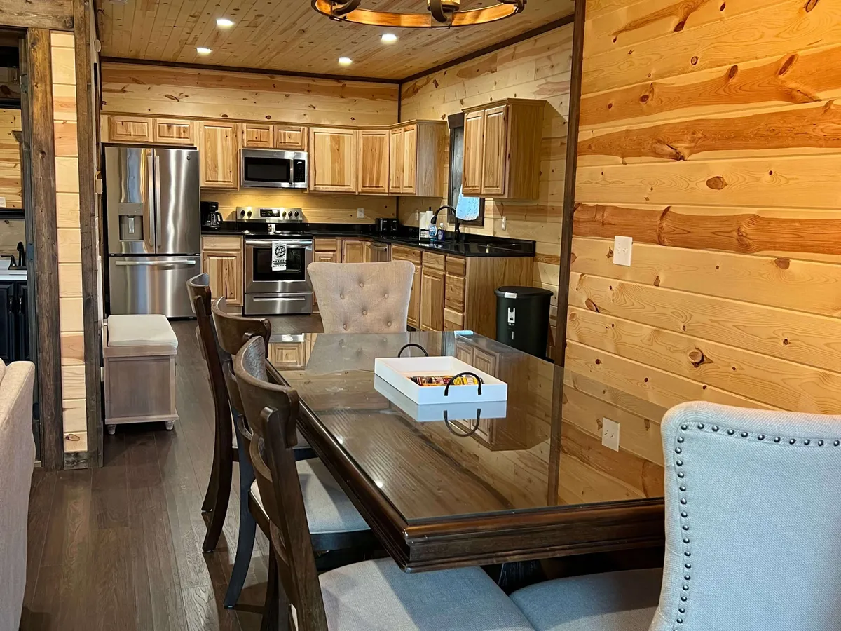 This image showcases a dining area seamlessly integrated with a fully equipped kitchen. The wooden paneling, modern appliances, and soft lighting create an inviting atmosphere for sharing meals, cooking together, and celebrating special moments.
