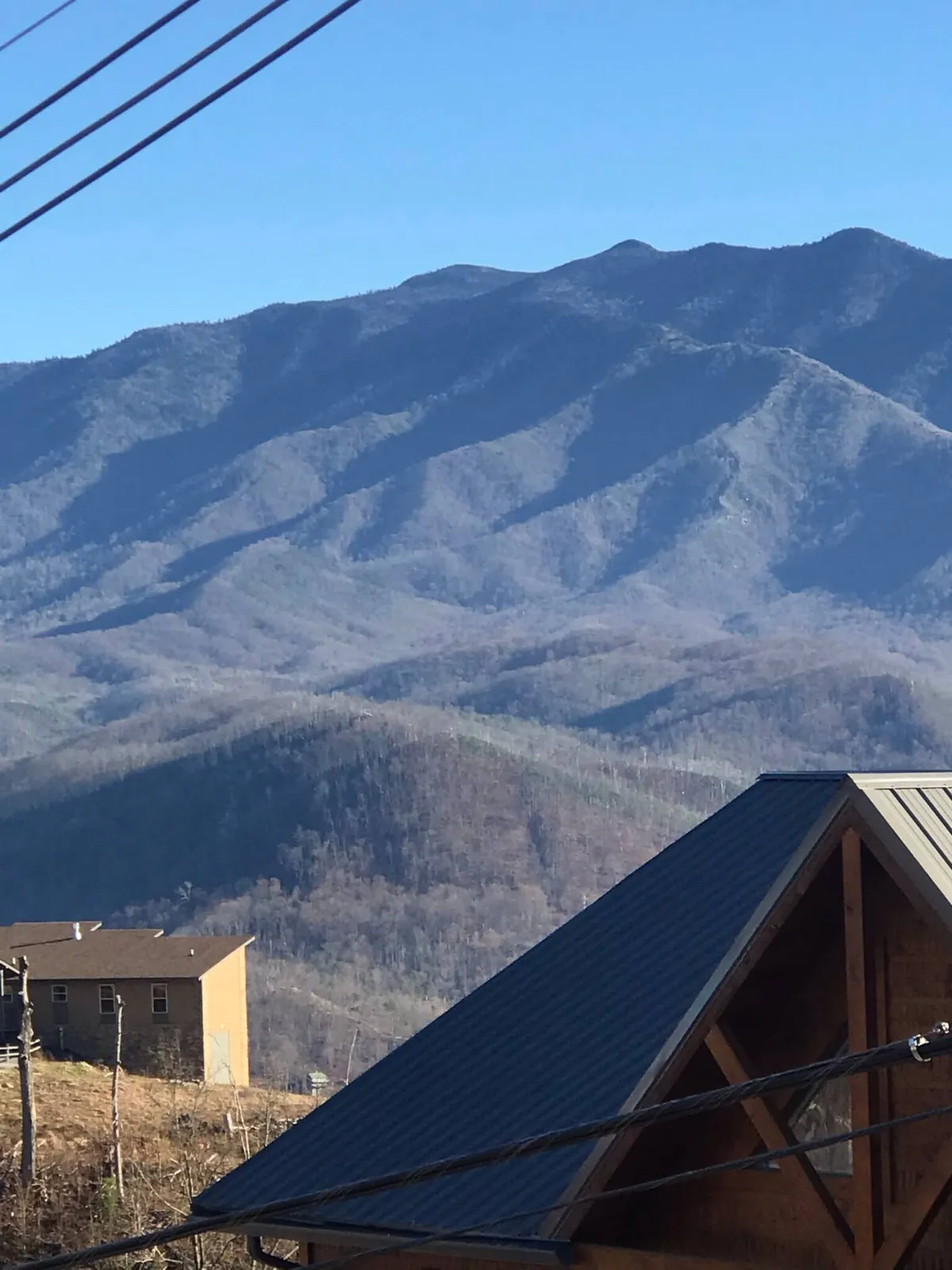 A sweeping view of a picturesque mountain range with scattered houses nestled among the landscape under a tranquil sky. The scene evokes a sense of adventure and connection with nature, ideal for families exploring the outdoors or relaxing together.
